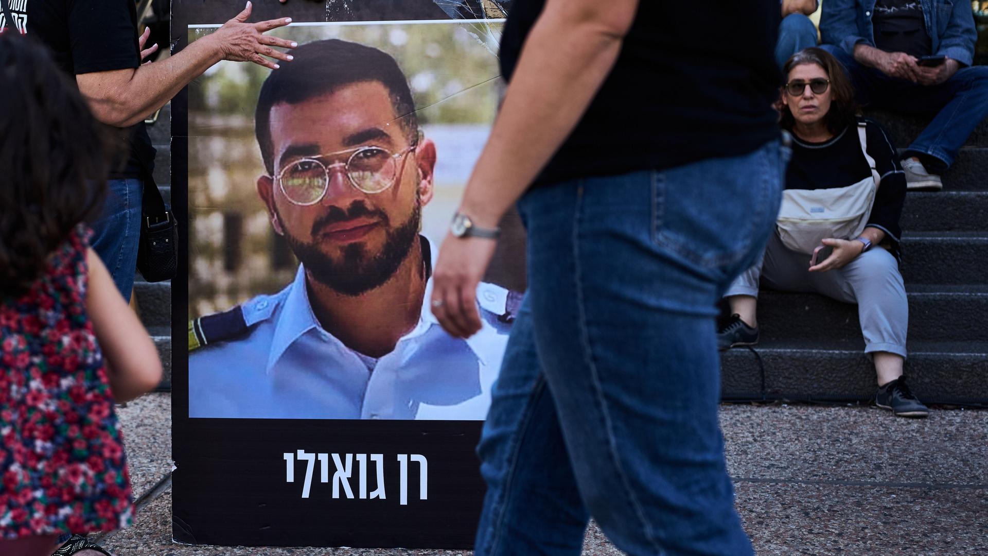 Straßenszene in Tel Aviv. Ein Mann hält seine Hand an ein Foto von Ran Gvili.