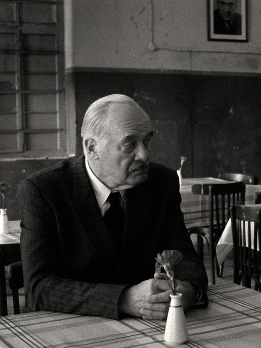 Szene aus einem Schwarz-Weiß-Film: Ein Mann und eine Frau sitzen an einem Tisch und schauen sich an. Szene aus einem Schwarz-Weiß-Film: Ein Mann und eine Frau sitzen an einem Tisch und schauen sich an.