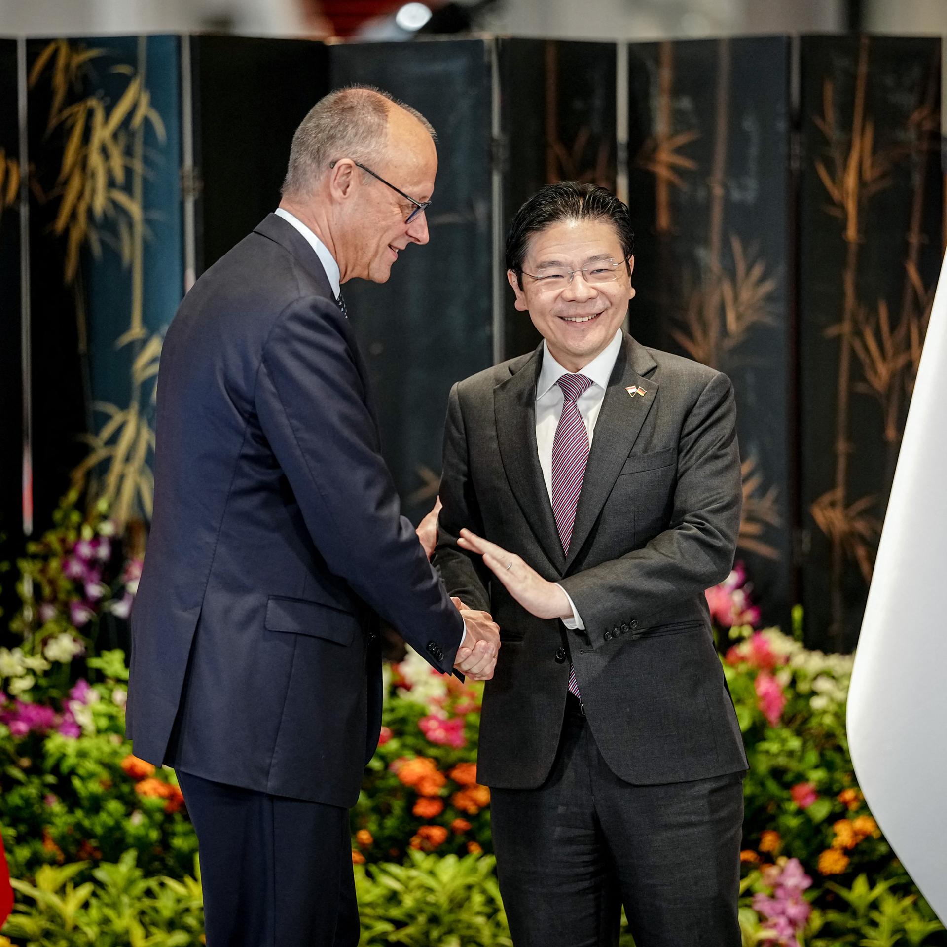 Bundeskanzler Merz (l.) und Singapurs Ministerpräsident Wong geben sich die Hand.