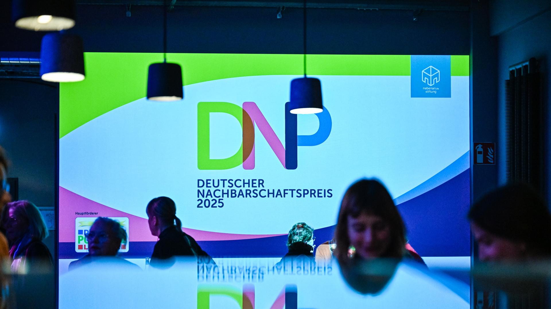 Man sieht eine Lein-Wand auf dem die Ab-Kürzung DNP steht. Das bedeutet: Deutscher Nachbrschafts-Preis