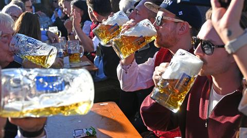 Mehrere Männer trinken Bier aus großen Gläsern in der Augustiner Festhalle auf dem 190. Oktoberfest 2025 auf der Theresienwiese.
