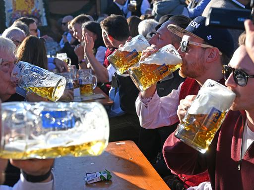 Mehrere Männer trinken Bier aus großen Gläsern in der Augustiner Festhalle auf dem 190. Oktoberfest 2025 auf der Theresienwiese.