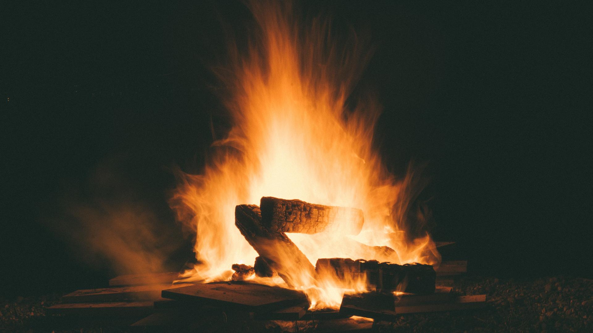 Blick auf ein großes Lagerfeuer mit glühenden Holzscheiten in der Nacht. Blick auf ein großes Lagerfeuer mit glühenden Holzscheiten in der Nacht.