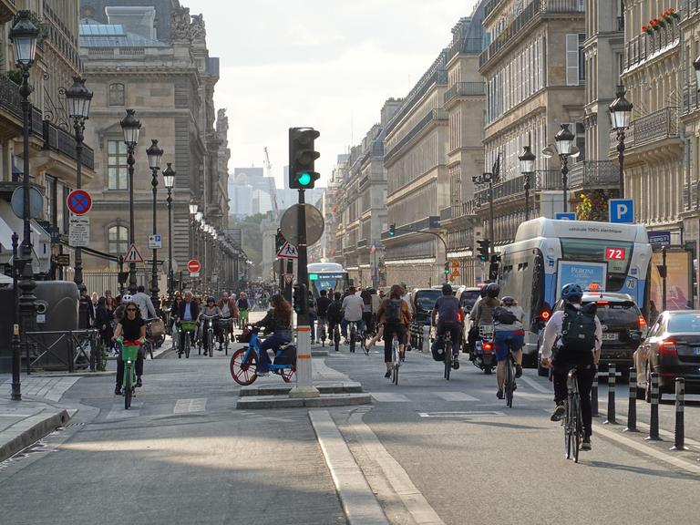Zahlreiche Fahrradfahrende bewegen sich durch die Rue de Rivoli in Paris.