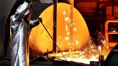 Ein Mitarbeiter von Thyssenkrupp zieht in silberner Schutzkleidung in Duisburg am Hochofen im Stahlwerk eine Probe