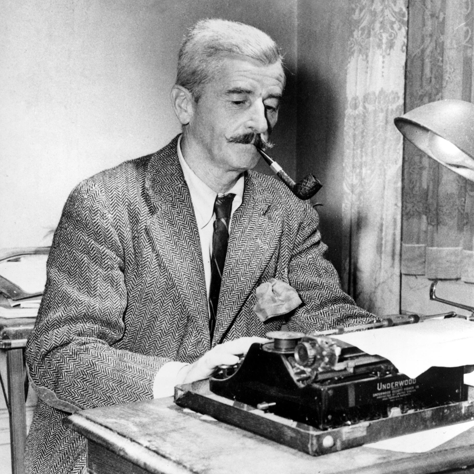 Das Schwarz-Weiß-Foto zeigt William Faulkner an seiner Schreibmaschine. Er trägt ein Tweed-Sakko und Schlips, raucht Pfeife und schaut konzentriert auf das eingespannte Blatt Papier.