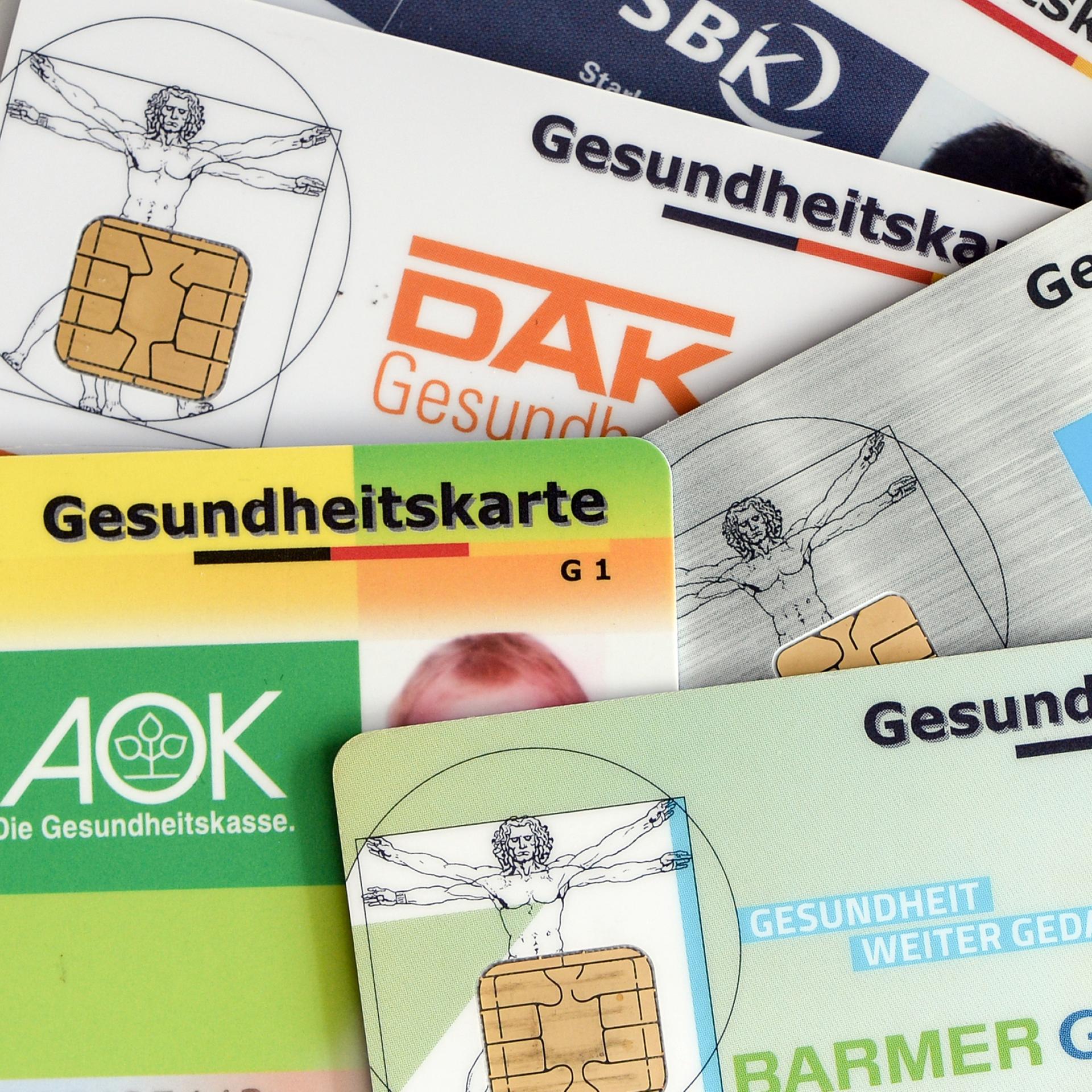 Gesundheitskarten verschiedener Krankenkassen liegen auf einem Tisch. 