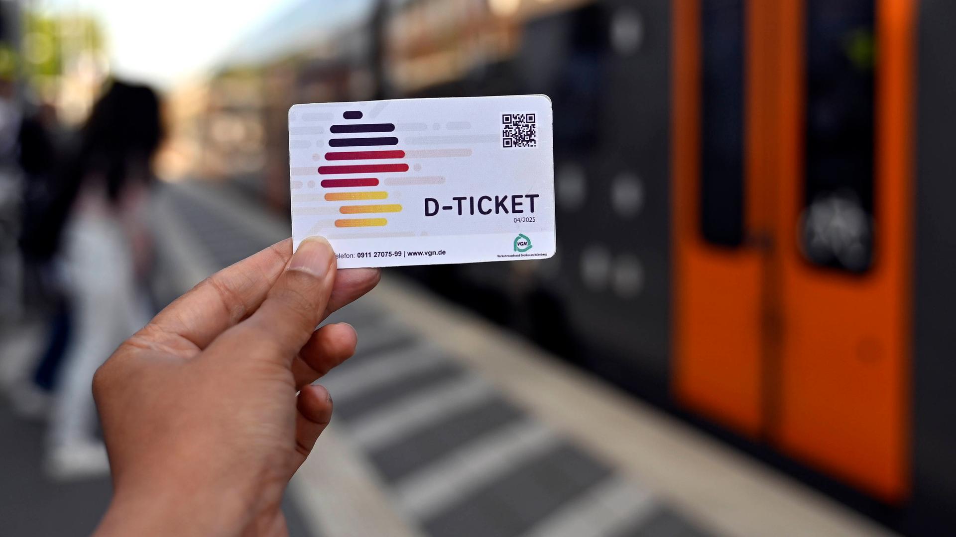 Eine Hand hält ein Deutschland-Ticket vor eine Zugtür der Deutschen Bahn. 