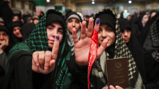 Mehrere junge Menschen stehen in einer Gruppe. Zwei von ihnen halten ihre rechte Hand in die Kamera. Auf ihren Zeigefingern ist ein blauer Tintenfleck zu sehen. Im Iran wird mit Fingerabdruck gewählt.