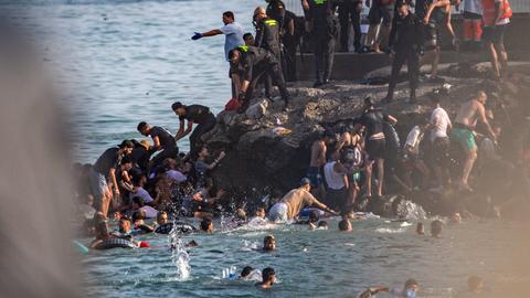 Migranten versuchen am 30. Juli 2026 von Marokko aus in die spanische Enklave Ceuta zu gelangen. Eine grosse Gruppe schwimmt und klettert die Felsen zum Grenzzaun hoch.