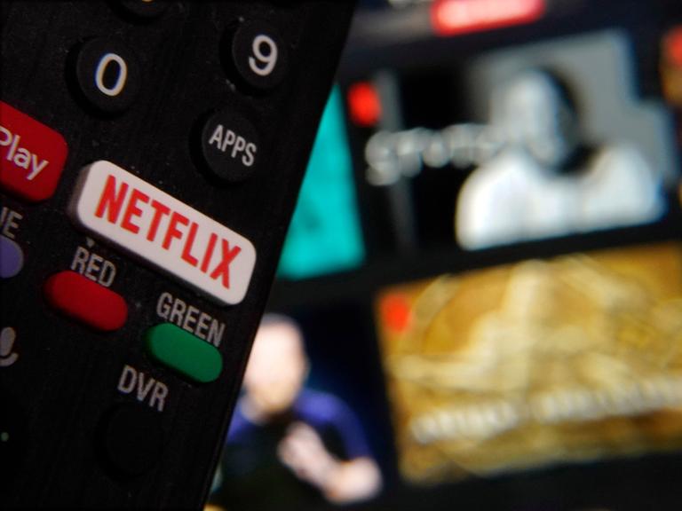 Ein eigener Netflix-Schaler auf der Fernbedienung, im Hintergrund ein TV-Bildschirm