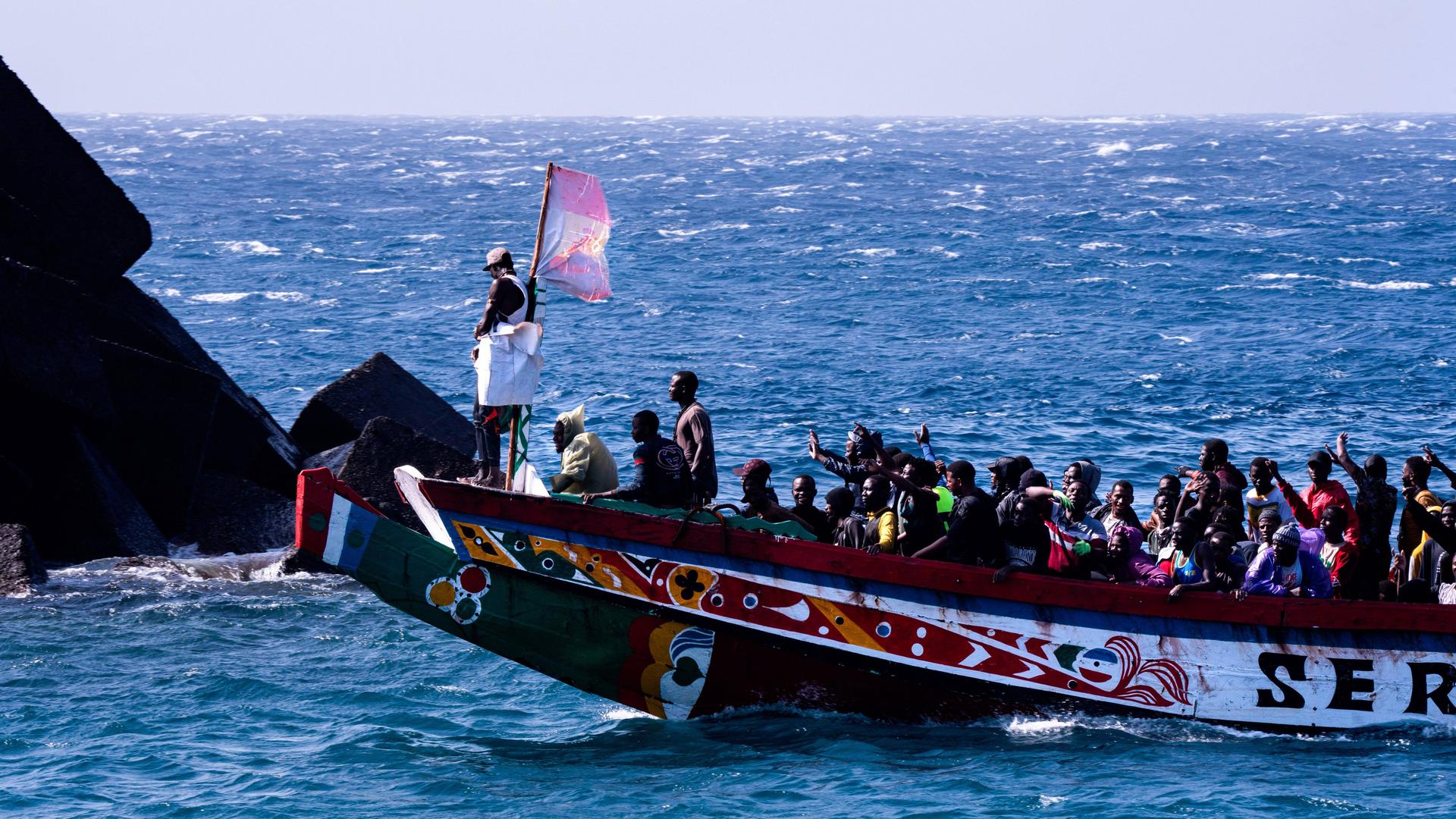 Eine Gruppe von Migranten feiert, dass sie die Überfahrt von Afrika nach Europa überlebt haben. Sie winken vom übervollen Boot. 358 Menschen erreichten im Laufe von drei Stunden die Kanareninsel El Hierro am 22. August 2024.