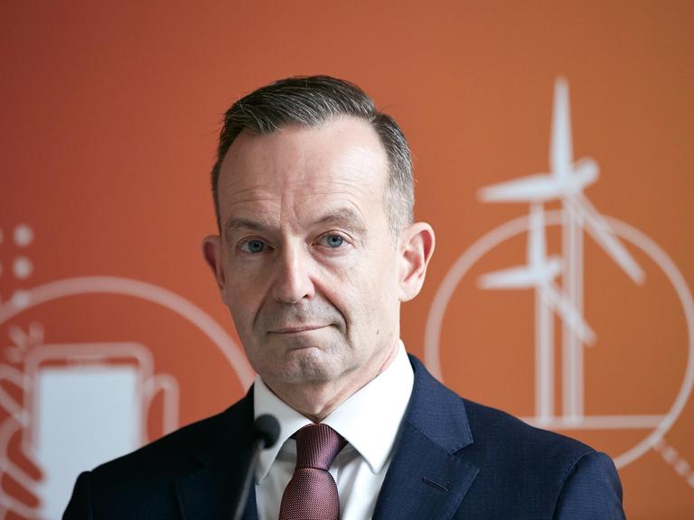 Bundesverkehrsminister Volker Wissing steht vor orangenem Hintergrund.