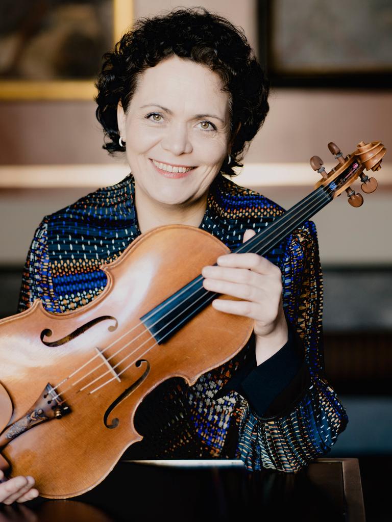 Eine Frau, die Bratschistin Tabea Zimmermann, hält eine Bratsche vor ihre Brust und lächelt