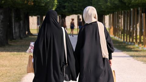 Zwei Frauen mit Kopftuch von hinten.