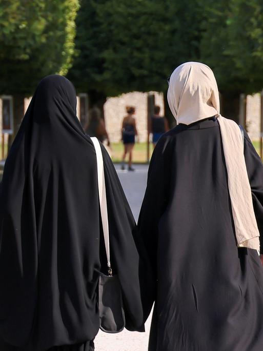 Zwei Frauen mit Kopftuch von hinten.