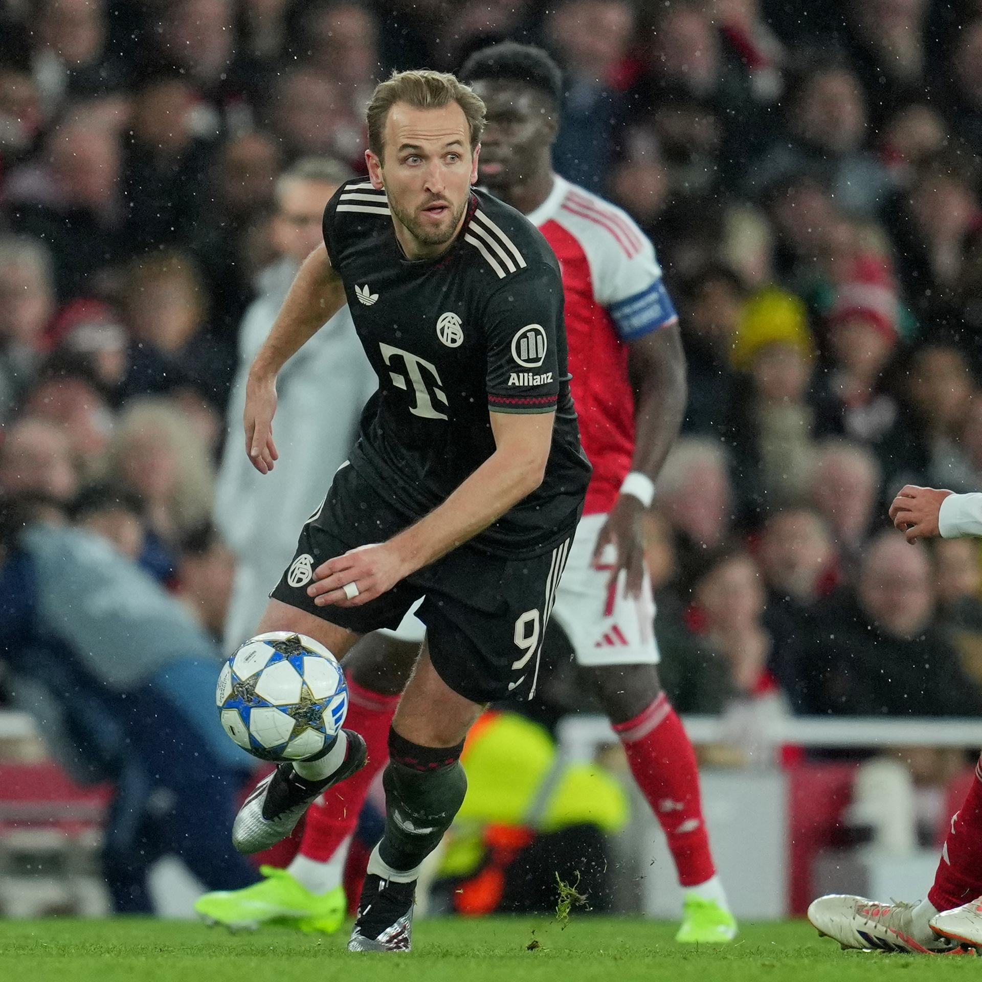 Kane im schwarzen Trikot treibt den Ball energisch vor Zubimendi im roten Trikot voran, der er überspielt hat.