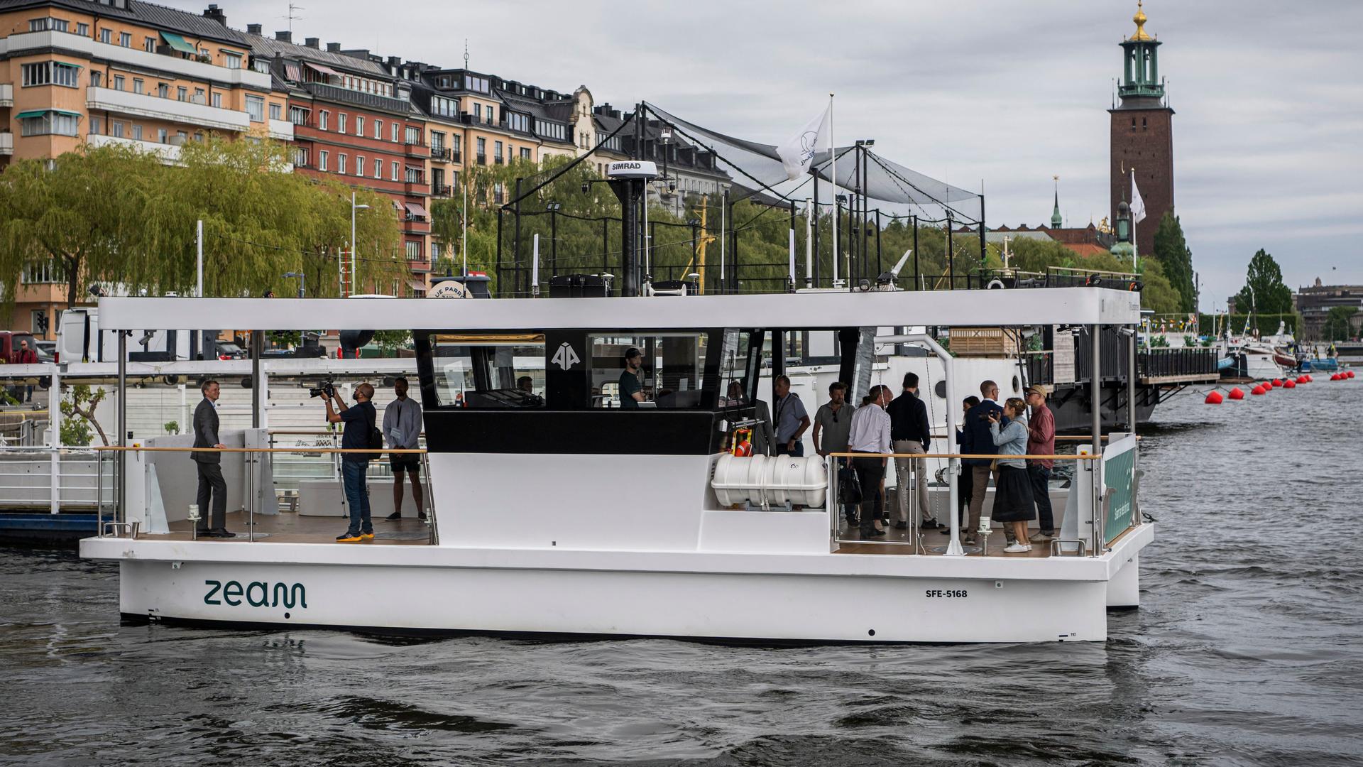 Die selbstfahrende Fähre "MF Estelle" fährt mit einigen Leuten an Bord durch den Hafen von Stockhlom. Die selbstfahrende Fähre "MF Estelle" fährt mit einigen Leuten an Bord durch den Hafen von Stockhlom.
