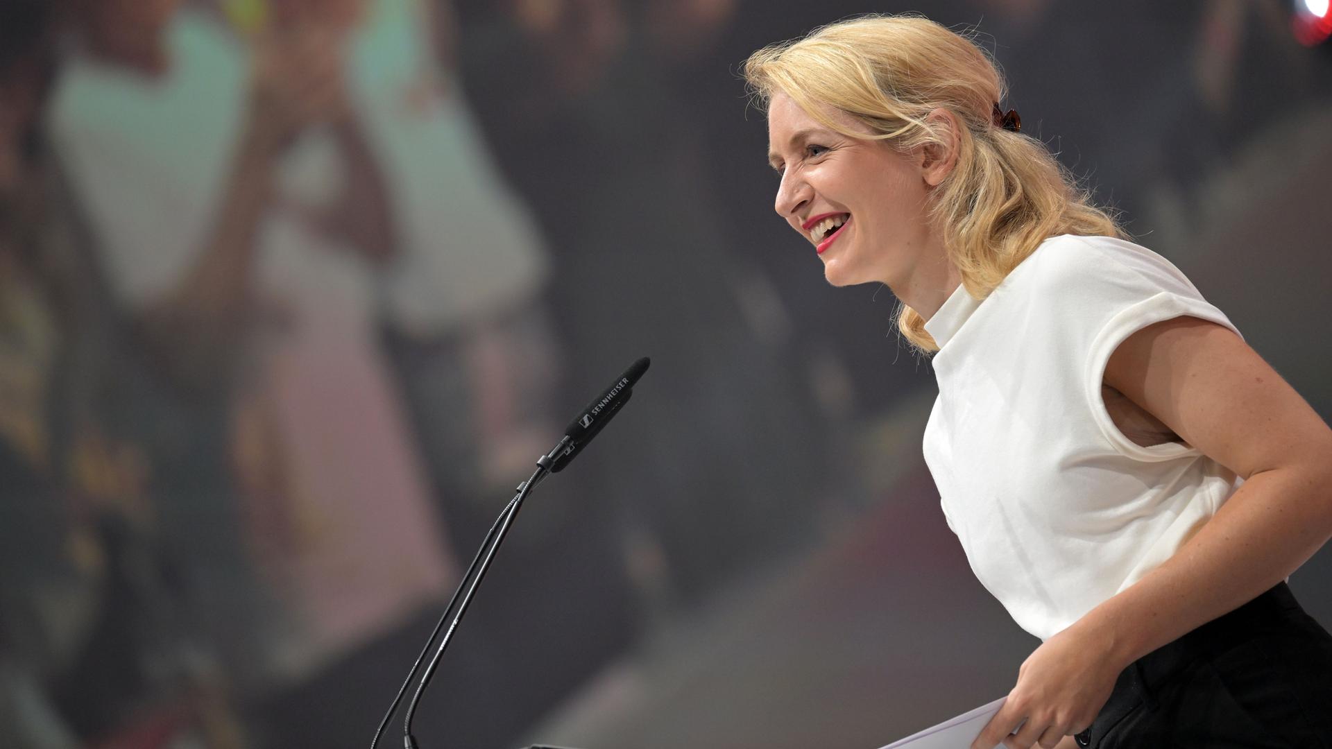 Ines Schwerdtner, die Vorsitzende der Linken, steht an einem Mikrofon und lächelt.