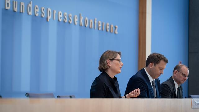 Lars Klingbeil und Stefanie Hubig sitzen vor dem blauen Hintergrund der Bundespresskonferenz. Rechts neben ihnen sitzt Tim Szent-Iványi .