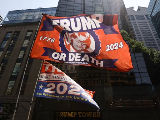 Vor dem Trump Tower hält ein Trump-Unterstützer am Tag nach dem Attentat auf Donald Trump eine Flagge auf der steht: Trump or Death, Trump oder Tod.