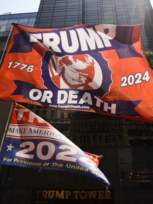 Vor dem Trump Tower hält ein Trump-Unterstützer am Tag nach dem Attentat auf Donald Trump eine Flagge auf der steht: Trump or Death, Trump oder Tod.