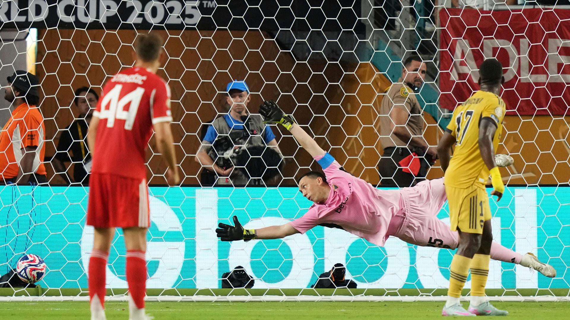 Der Torhüter der Boca Juniors, Agustin Marchesin, taucht ab, als er ein Tor von Bayern Münchens Michael Olise (nicht im Bild) nicht verhindern kann. Der Torhüter der Boca Juniors, Agustin Marchesin, taucht ab, als er ein Tor von Bayern Münchens Michael Olise (nicht im Bild) nicht verhindern kann.