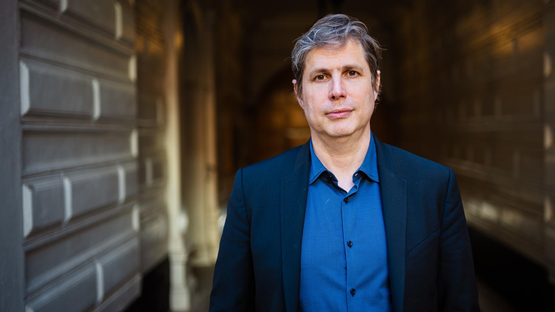 Der Schrifsteller Daniel Kehlmann steht in einem Hausflur