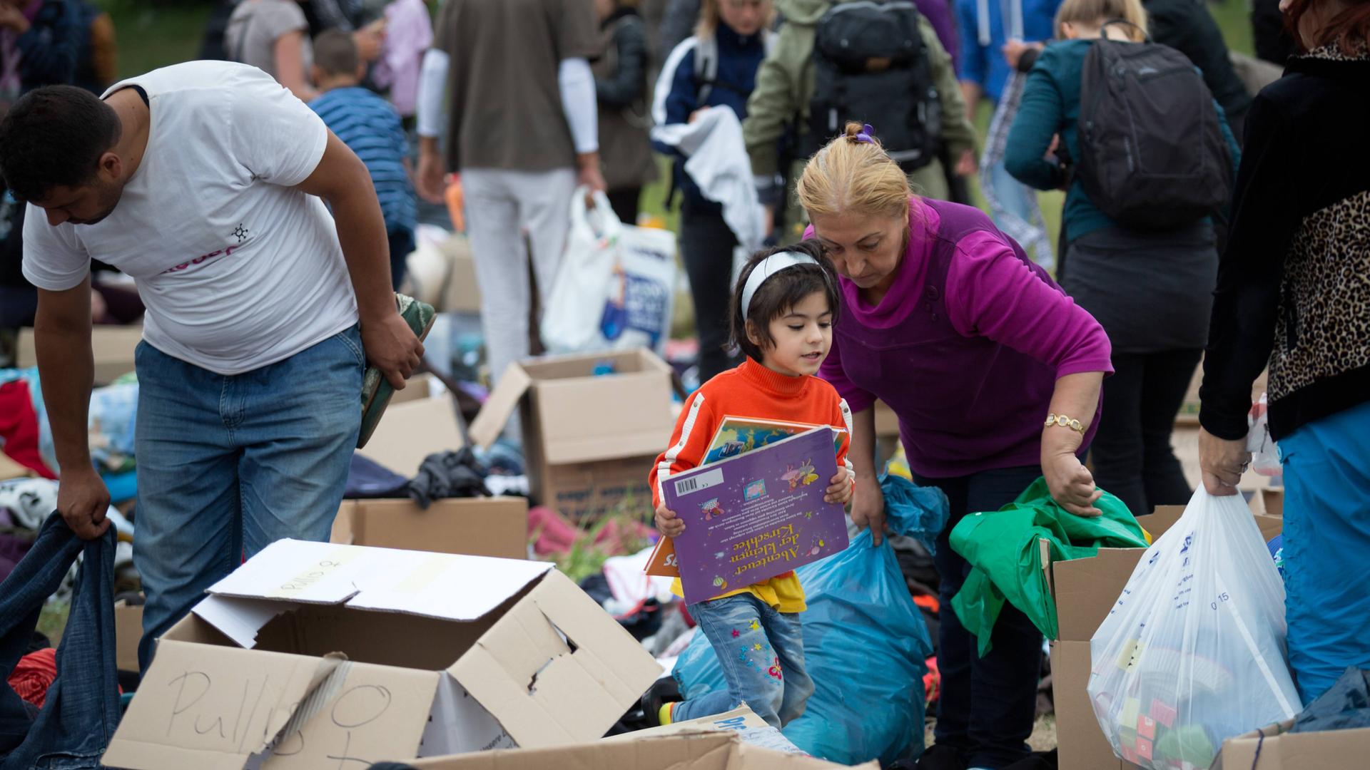 Geflüchtete stöbern bei einem Willkommensfest für Flüchtlinge in Heidenau 2015 in Spenden-Kisten. Geflüchtete stöbern bei einem Willkommensfest für Flüchtlinge in Heidenau 2015 in Spenden-Kisten.