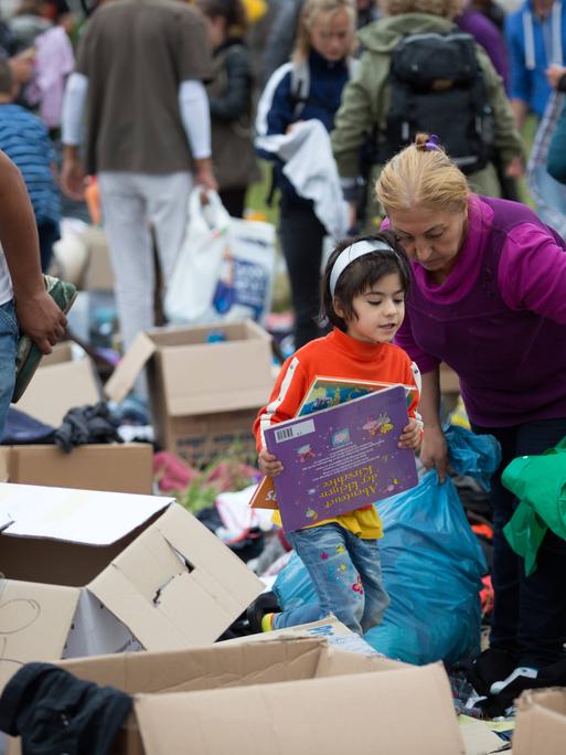Geflüchtete stöbern bei einem Willkommensfest für Flüchtlinge in Heidenau 2015 in Spenden-Kisten. 