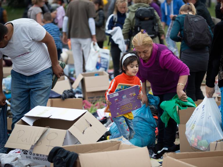 Geflüchtete stöbern bei einem Willkommensfest für Flüchtlinge in Heidenau 2015 in Spenden-Kisten. 