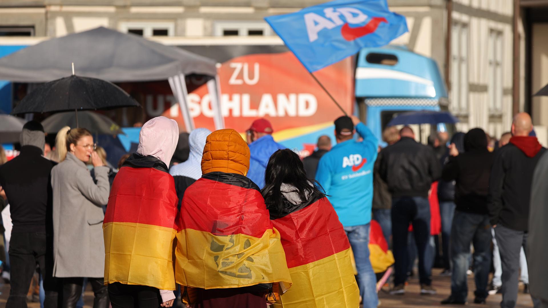 Drei mit Deutschlandfahnen behängte Teenager nehmen an einer Wahlkampfveranstaltung der AfD in Haldensleben teil.