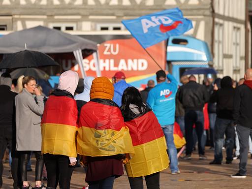 Drei mit Deutschlandfahnen behängte Teenager nehmen an einer Wahlkampfveranstaltung der AfD in Haldensleben teil.