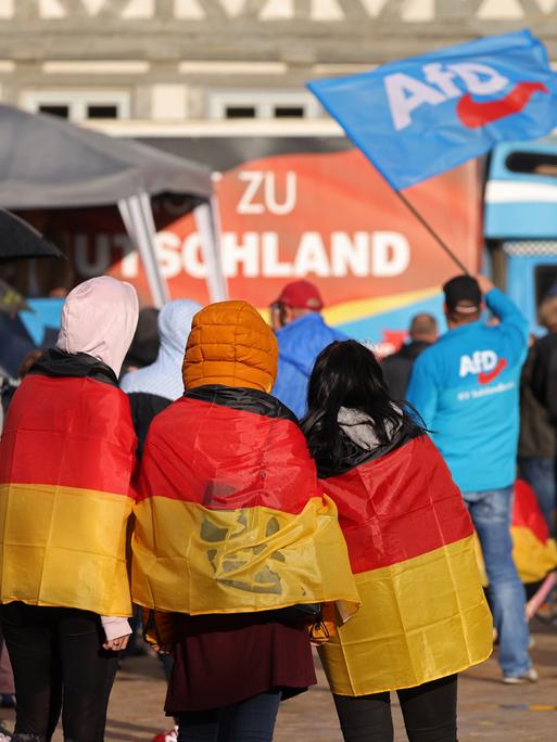 Drei mit Deutschlandfahnen behängte Teenager nehmen an einer Wahlkampfveranstaltung der AfD in Haldensleben teil.