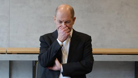 Bundeskanzler Olaf Scholz fasst sich an die Nase. 