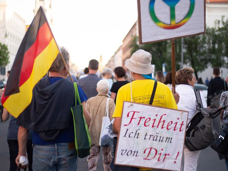 Menschen auf einer Demonstration. Ein Mann mit einem Plakat auf dem Rücken: Freiheit ich träum von Dir!