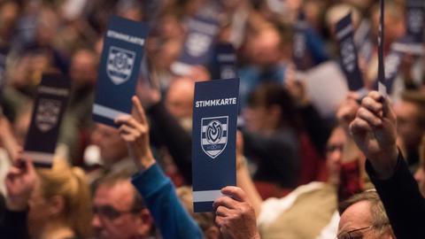 Bei der Jahreshauptversammlung des MSV Duisburg werden Stimmkarten hochgehalten.