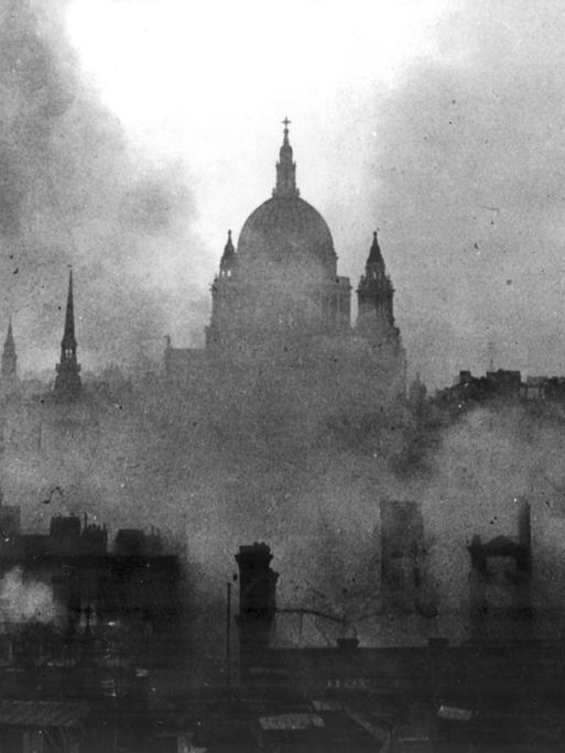 Schwarz-Weiß-Aufnahme zeigt die St Pauls Cathedral in London umgeben von Rauchschwaden.