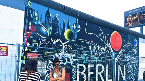 Blick auf die bemalte Mauer im Bereich der East Side Gallery mit Musiker und Publikum davor. Blick auf die bemalte Mauer im Bereich der East Side Gallery mit Musiker und Publikum davor.