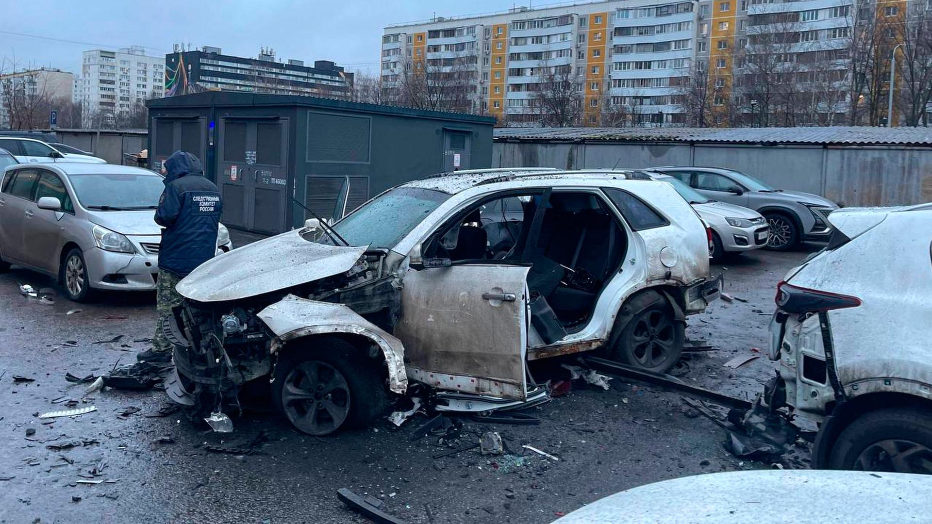 Ein Ermittler arbeitet am Tatort, an dem eine Bombe ein Auto zerstört hat.