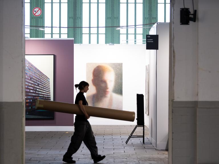 Eine Frau geht während der Pressekonferenz zur Kunstmesse "Positions Berlin Art Fair im Hangar 4 des Flughafens Tempelhof an Bildern vorbei. Die Messe fand vom 12. bis 15. 09.2019 statt. 