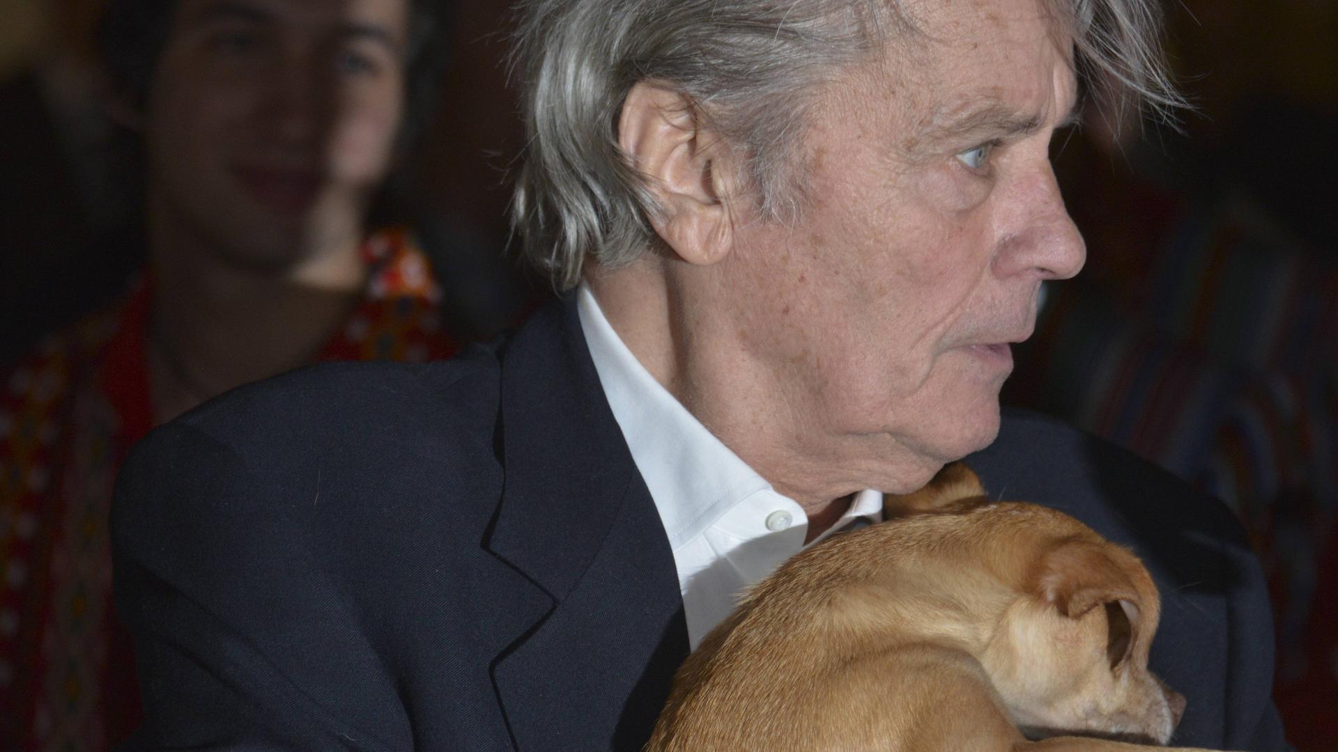Der Schauspieler Alain Delon hält einen Hund auf dem Arm. Der Schauspieler Alain Delon hält einen Hund auf dem Arm.