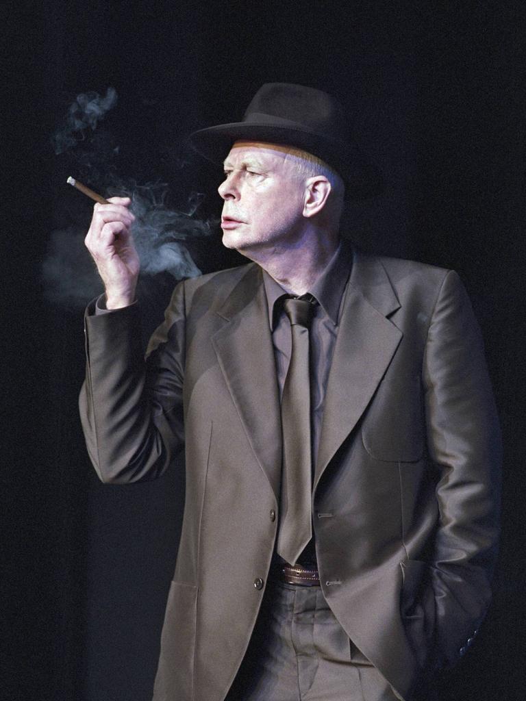Alexander Lang (Schauspieler und Regisseur), geb. am 24.09.1941 in Erfurt, hier als Friedrich Hofreiter in Das weite Land. Vor schwarzem Hintergrund trägt er einen schwarzen Anzug, einen schwarzen Hut und raucht eine Zigarre.