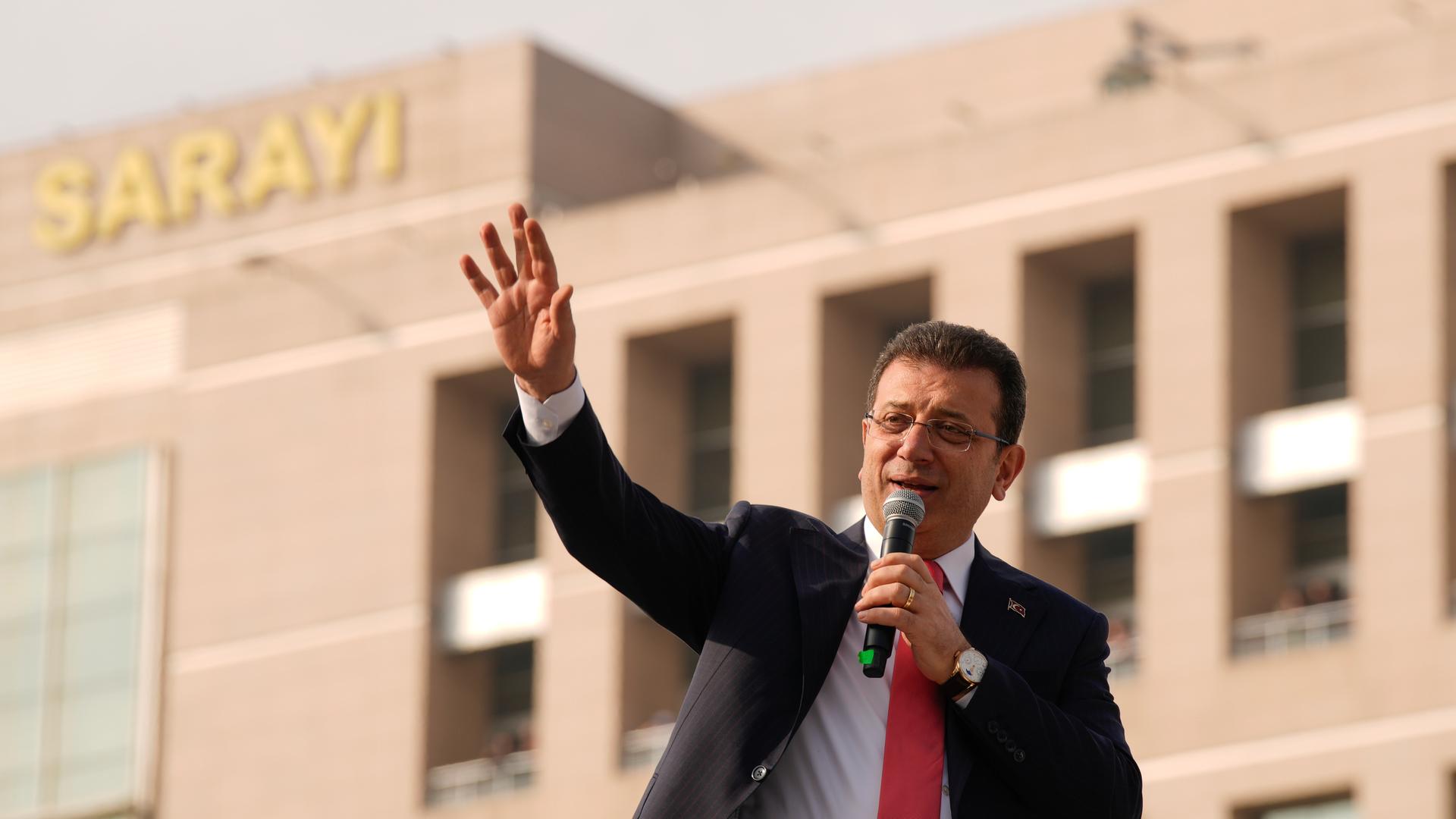 Der Politiker Ekrem Imamoglu spricht in ein Mikrofon. Er hebt einen Arm in die Höhe.