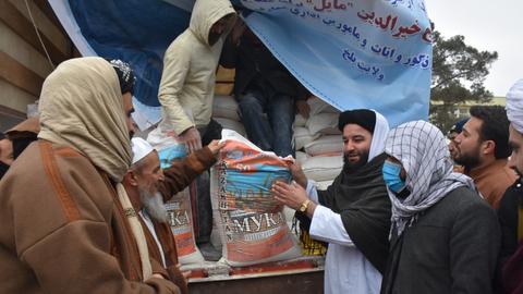Afghanische Männer vor einem Lastwagen mit Hilfslieferungen.  