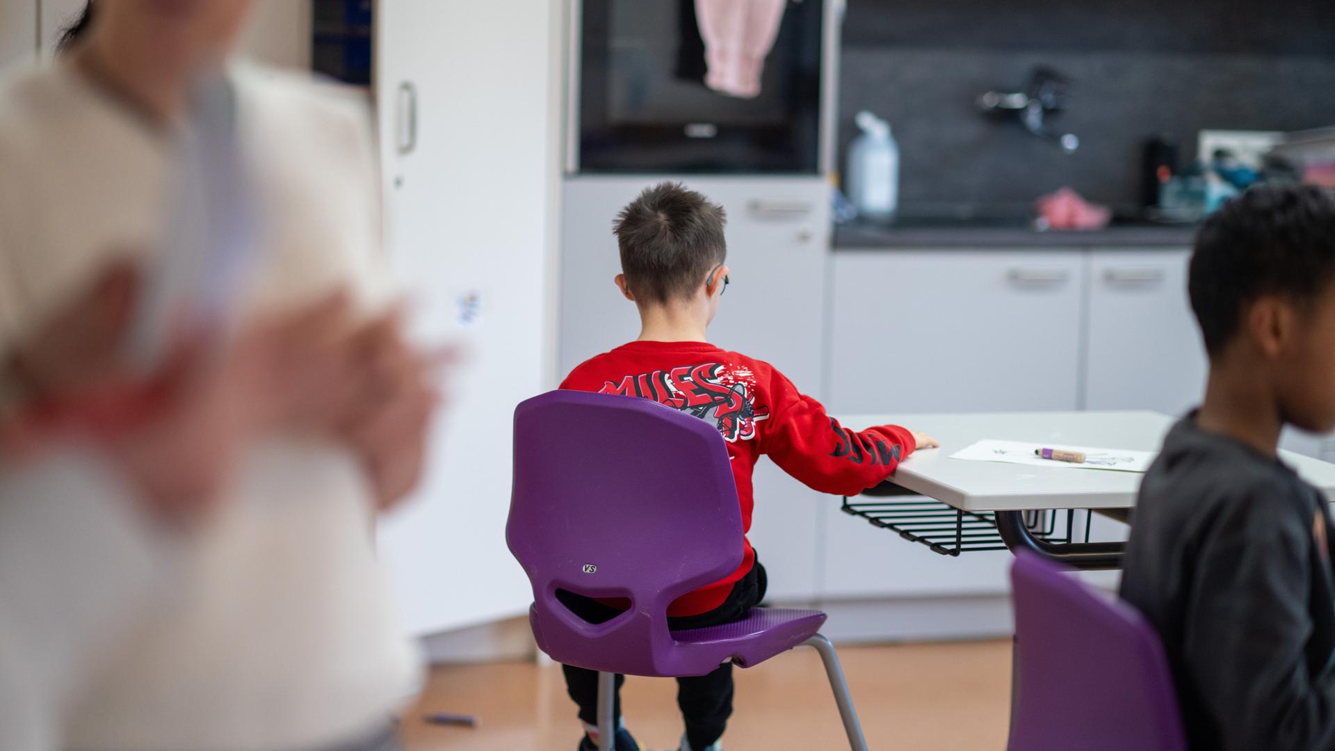 Im Förderunterricht an einer Förderschule sitzt im Klassenraum ein Schüler etwas abseits.