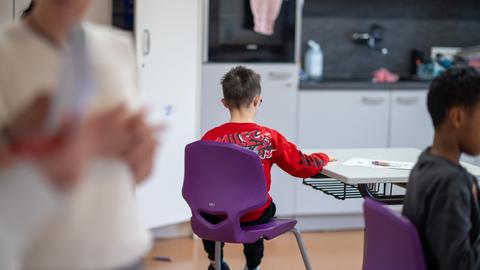 Im Förderunterricht an einer Förderschule sitzt im Klassenraum ein Schüler etwas abseits.