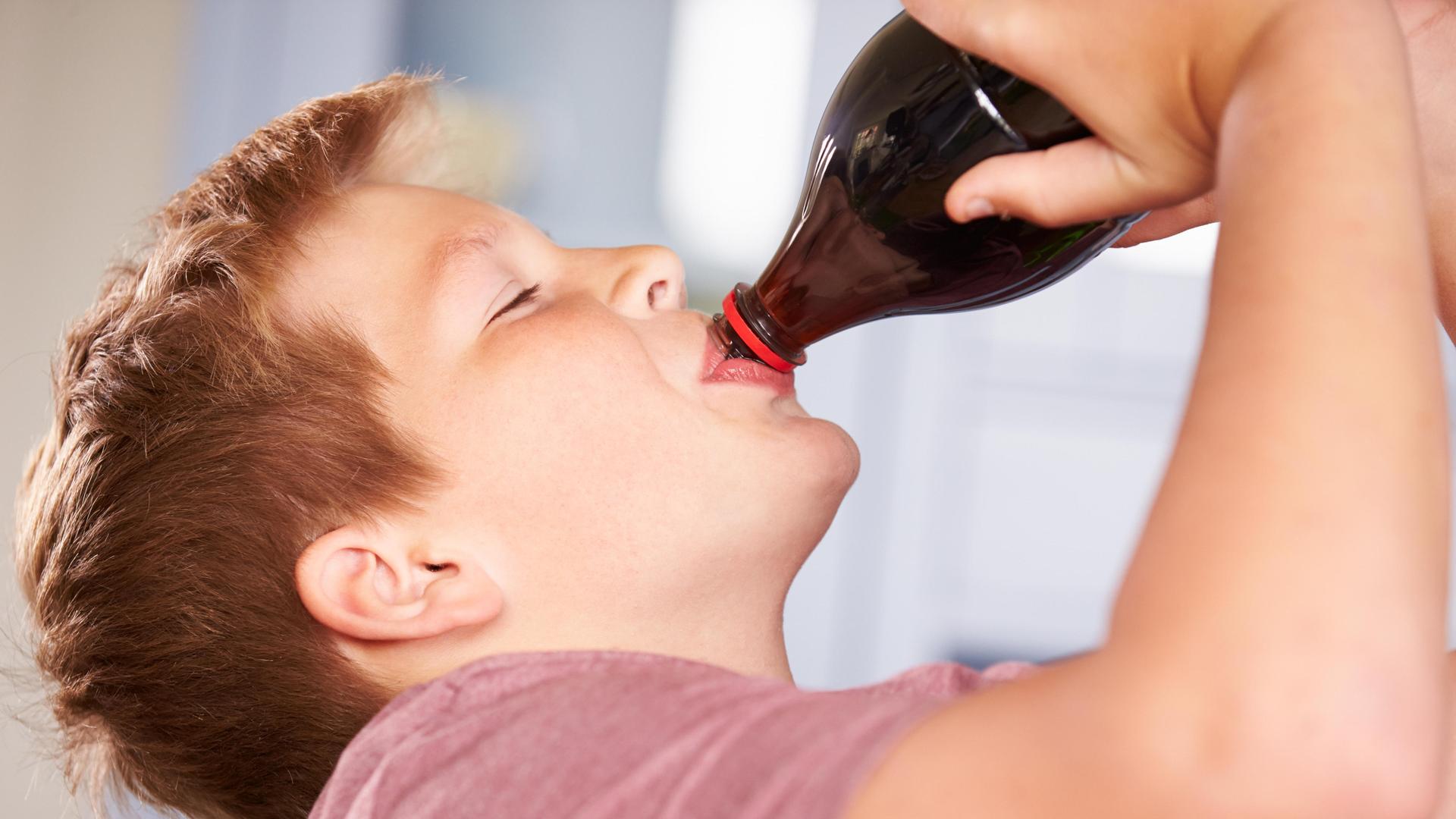 Ein Junge trinkt aus einer Flasche.