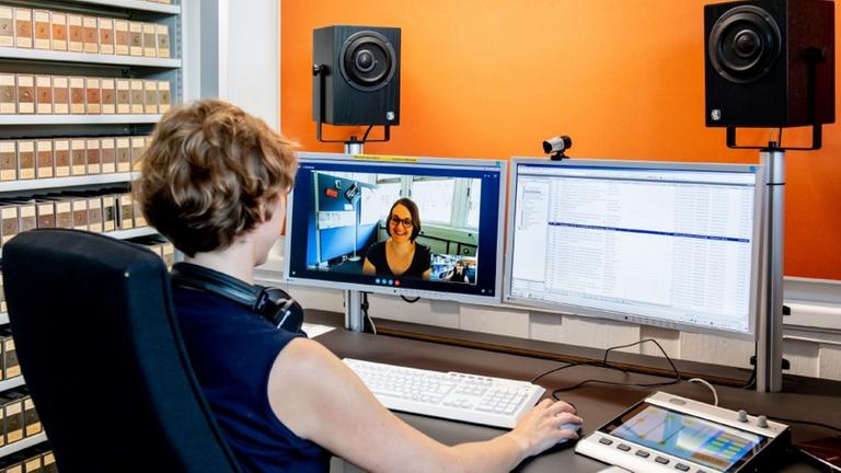 Frau sitzt am Computer mit zwei Bildschirmen und hält Videokonferenz mit einer Frau