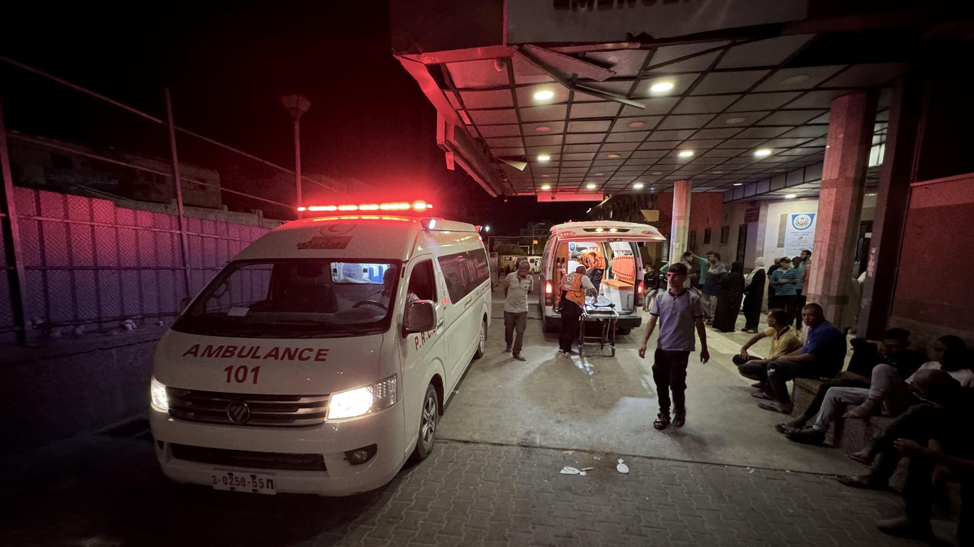 Ein Krankenwagen steht vor dem Eingang eines Krankenhauses. Es ist dunkel.